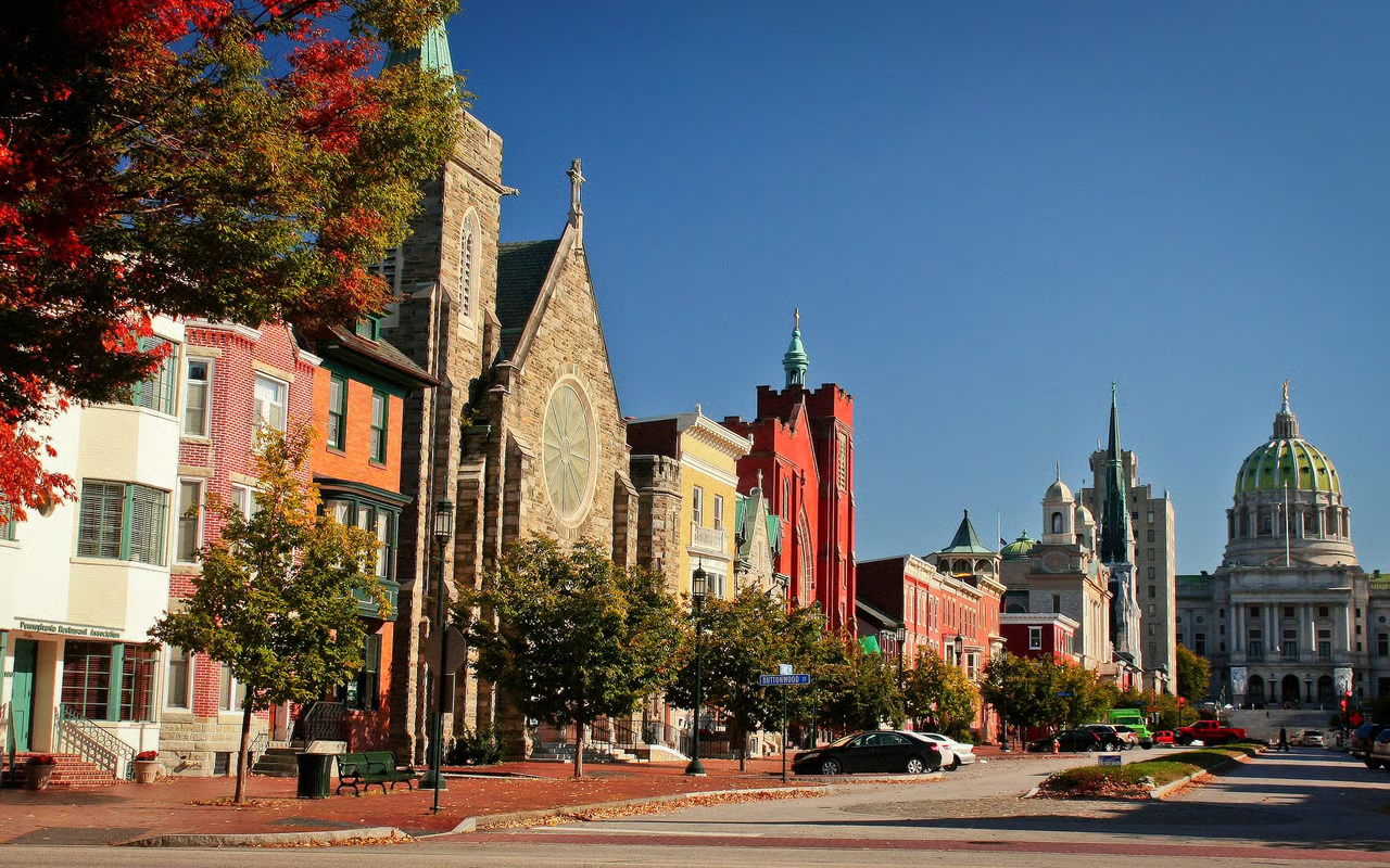 Colorful historic village street with classic stone church, row buildings and autumn trees, representing Sewickley community living